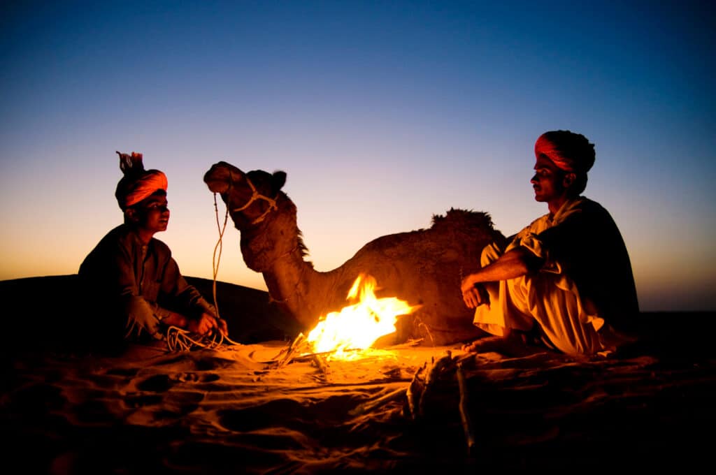 Overnight desert safari with a campfire, traditional Bedouin tents, and starlit sky over the sand dunes